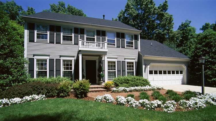 Grey two story home with black roof, front door and shutters.